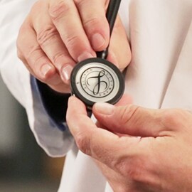 Close up of a doctor holding the chestpiece of a 3M Littmann Stethoscope.