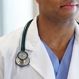 Littmann stethoscope properly worn outside the collar of a white lab coat.